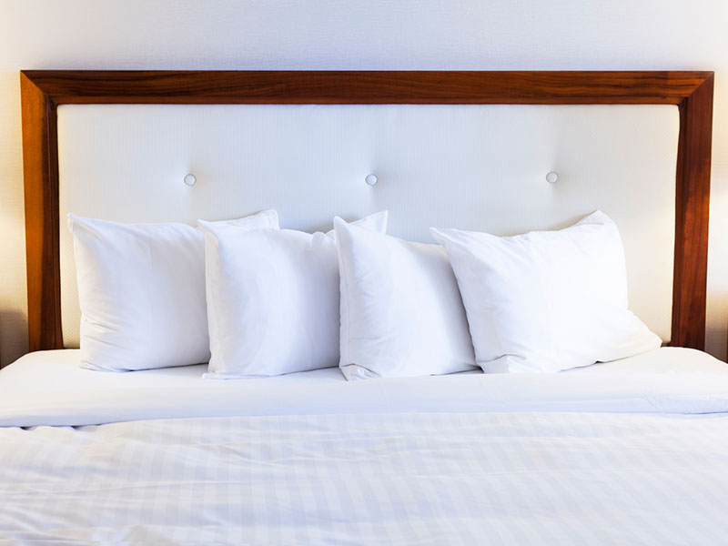 White bed and headboard, with four white bed pillows.